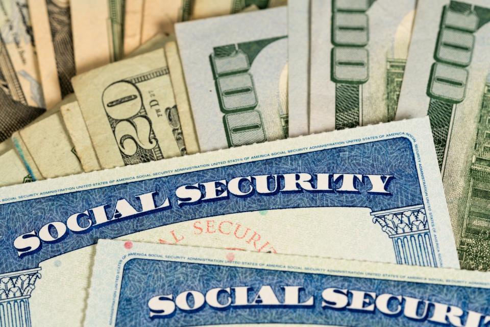 Two social security cards placed on top of a pile of money.